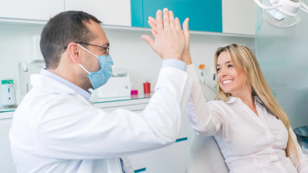 Dentist and patient highfiveing over getting invisible aligners